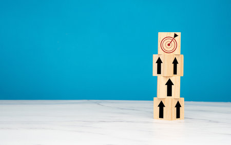 Business growth concept. Wooden cubes with black arrows up point to an aim in a dartboard icon over...