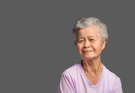 Portrait of an elderly Asian woman with short grey hair looking at the camera with a smile while...