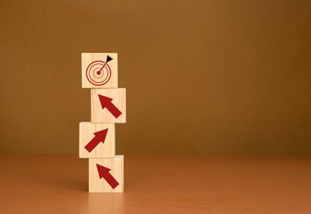 Business growth concept. Wooden cubes with red arrows up point to an aim in a dartboard icon. Focus on a goal and achieve a successful businessの写真素材