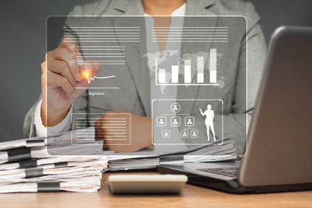 A businesswoman in a suit uses a pen to sign electronic documents on a virtual screen while sitting...