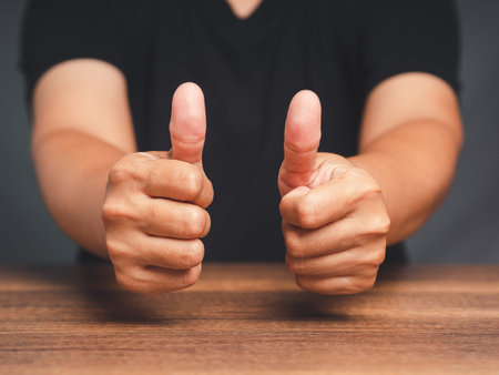 A young man's giving a thumbs up to the success and best service. Customer service and satisfaction surveys conceptの写真素材
