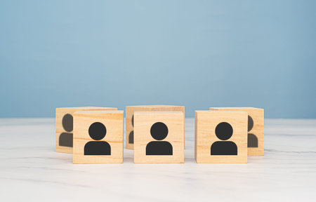 Wooden cubes with people icons over a marble table with a light blue background. Teamwork and unity concept. Space for text. Close-up photoの写真素材