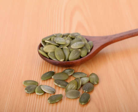 pumpkin seeds in wooden spoon on wood tableの写真素材