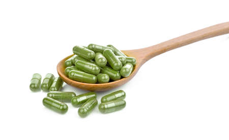 moringa oleifera capsule in wooden spoon isolated on white backgroundの写真素材