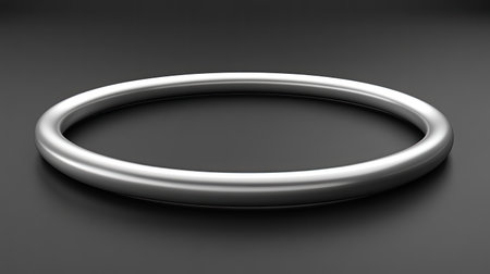 This image features a sleek circular metal ring set against a dark backdrop. The minimalist design emphasizes the ring's smooth surface and reflective quality, making it perfect for creative, artistic, and design projects.の素材