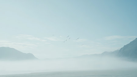 This tranquil landscape features misty mountains with birds soaring in a clear blue sky, creating a serene atmosphere perfect for nature lovers.の素材