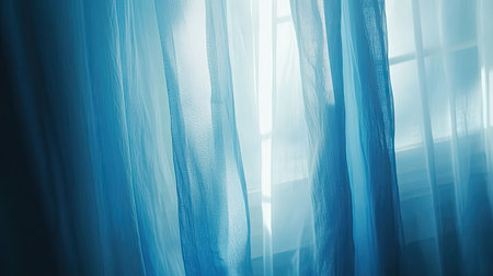 A peaceful scene featuring sheer blue curtains gently swaying in soft morning light, creating an atmosphere of tranquility and warmth in an indoor setting.の素材