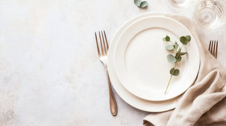 This image showcases an elegant table setting featuring a white plate and fork alongside a soft cloth napkin and fresh greenery, perfect for dining occasions.の素材