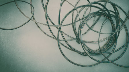 An abstract and artistic image featuring a tangled arrangement of metallic wires on a soft background, perfect for creative projects, design inspiration, and visual storytelling.の素材