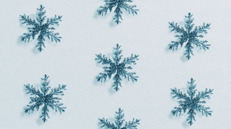 This image features an arrangement of beautiful blue snowflakes on a soft white background, ideal for winter-themed designs and seasonal decorations.の素材