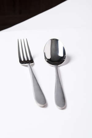 Stainless steel spoon and fork on white paper.の写真素材