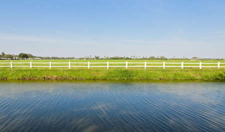 White fence with green fieldの写真素材