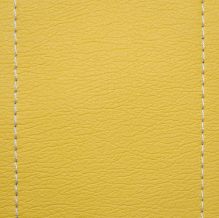 Bright yellow leather texture background with white stitchの写真素材