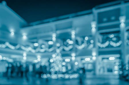 Blurred abstract city night life background with people walking on urban street in blue tone color imageの写真素材