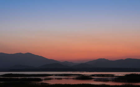 Beautiful sunset over the mountain with reflection on lakeの写真素材