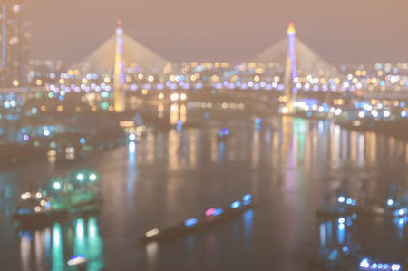 Blurred city skyline bokeh lights illuminated at night with reflection on riverの写真素材