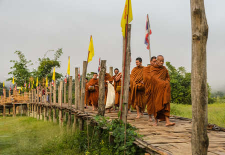 MAE HONG SON, THAILAND - NOVEMBER 21, 2015: Morning Buddhist Almsgiving at Zu Tong Pae bamboo bridge in Mae Hong Son, Thailand.  Monks  go on a daily almsround to collect food.のeditorial素材