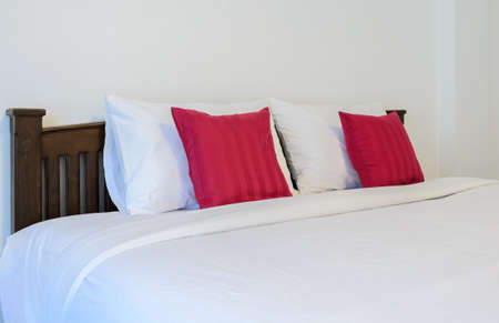 White bedroom with tidy King size bed and red pillowsの写真素材
