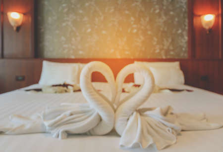 Blur image background of white swan towel on bed with warm light bedroomの写真素材