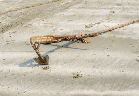Small rusty boat anchor in the sand on beachの写真素材