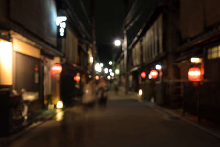 Abstract blur people walking on narrow street of wooden store and restaurant with lighted lanterns at night in Kyoto, Japanの写真素材