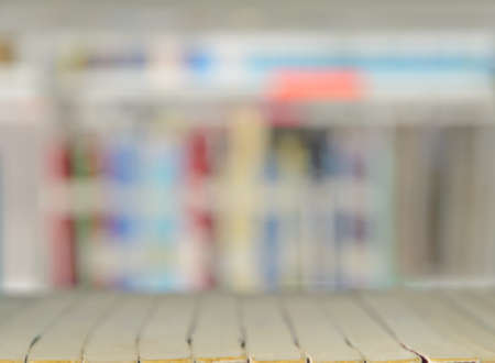 Blurred abstract background of softcover books stacked up on shelf with blurry multicolored books backgroundの写真素材