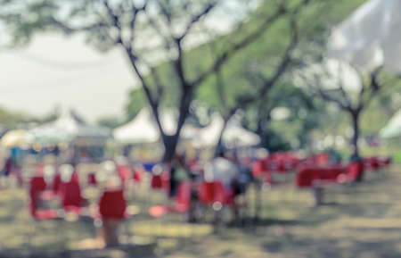 Blurred image of a fair in green park. Abstract background for festival and market. Vintage filtered effect imageの写真素材