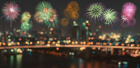Colorful fireworks on skyline background with blurred city night illuminated lights bokehの写真素材