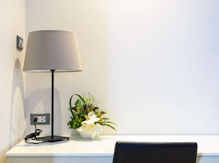 Wooden working desk with table lamp in a white hotel room, bedroom interiorの写真素材