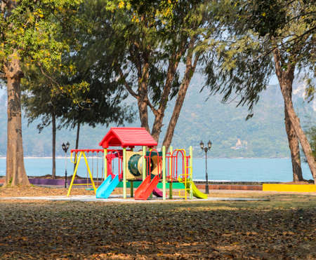 Colorful childrens playground near the sea, mountain on background. Plastic slides and climbers in public parkの写真素材