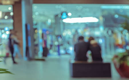 Abstract blurred background of couple resting in front of store in shopping mallの写真素材