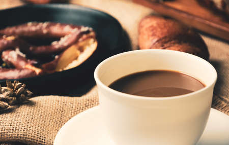 Coffee white cup with croissant and pretzel on sackcloth fabric. Breakfast conceptの写真素材