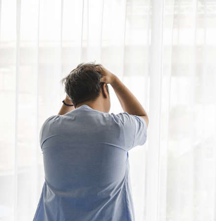 Back view of Asian male patient pain and stress on her sickness in hospital room. Healthcare...
