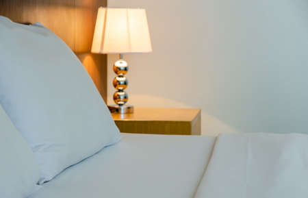 Bed with white pillow and sheet with table light lamp decoration in bedroom interiors