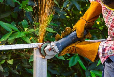 Worker wearing safety leather gloves with goggles and grinding arc welding strikes of structural...