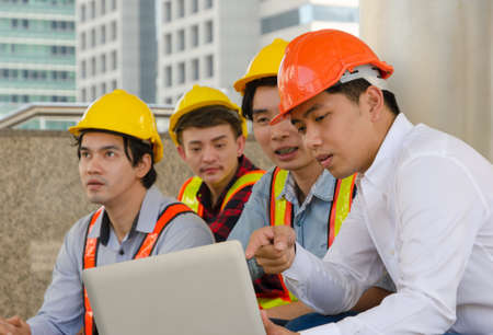 Engineering team sitting outdoors analyzing projects and checking work plan on laptop. Engineer or...