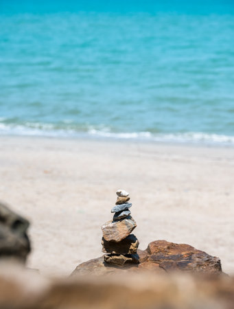 Stack of pebble stones on a big rock at the beach on blue sea background. Concept of harmony and...