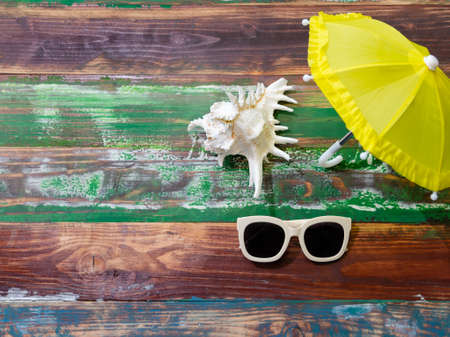 Summer background with beach accessories of white sunglasses and yellow umbrella on weathered wooden backgroundの写真素材