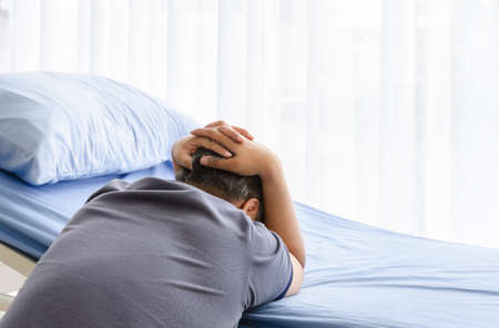 Depressed elderly spouse man mourning on patient bed for gone wife in hospital roomの写真素材