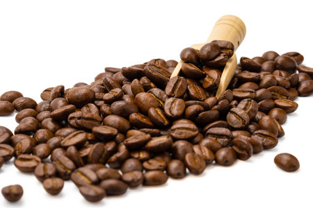Roasted coffee beans with small wooden scoop isolated on white background, selective focusの写真素材