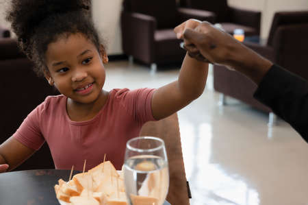 Smiling daughter giving fist bump to black father while waiting in airport lounge for flightの写真素材
