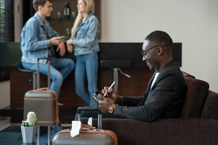 Businessman sitting on sofa at the airport lounge, waiting for the flight. Smiling man using digital tablet for presentation or new ideas of business project.の写真素材