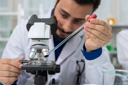 Male scientist in white lab coat dropping chemical liquid on slide and using microscope in laboratory research and development. Science and Technology conceptの写真素材