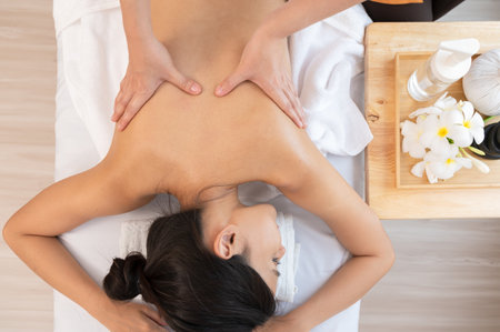 Masseur hands make back massage with aromatherapy essential oil for young attractive woman on massage table at spa salon, top view image.の写真素材