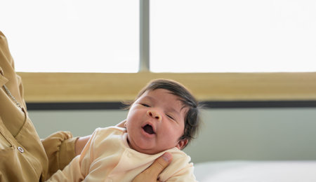 Adorable newborn baby girl yawn sleepy on mom hands. Healthy newborn baby conceptの写真素材