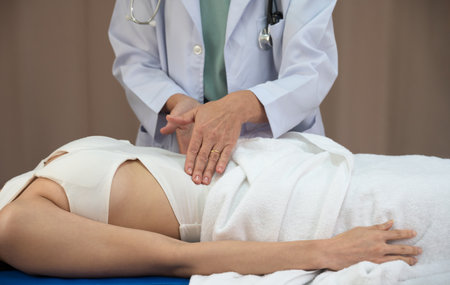 Closeup of doctor examines or treatment abdomen of female patient on bed in hospital. Health care and insurance conceptの写真素材