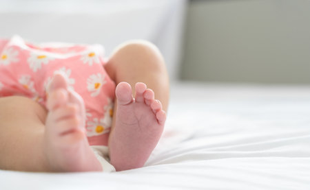 Tiny feet of newborn. Soft feet of baby on white blanket at home. Selective focus.の写真素材