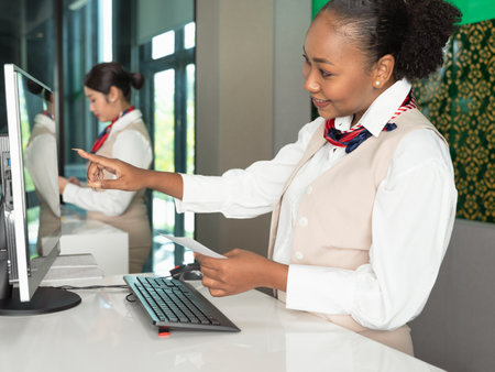 Smiling african airline attendent woman working at check-in desk in airportの写真素材