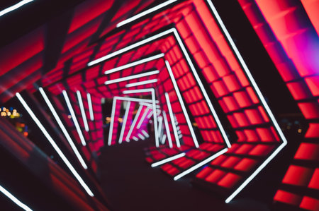 Futuristic neon tunnel with geometric abstract blur background . Vibrant red backdrop contrasts with white LED lines forming angular shapes.の写真素材