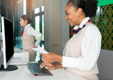 Smiling african airline attendant woman working at check in desk in airportの写真素材